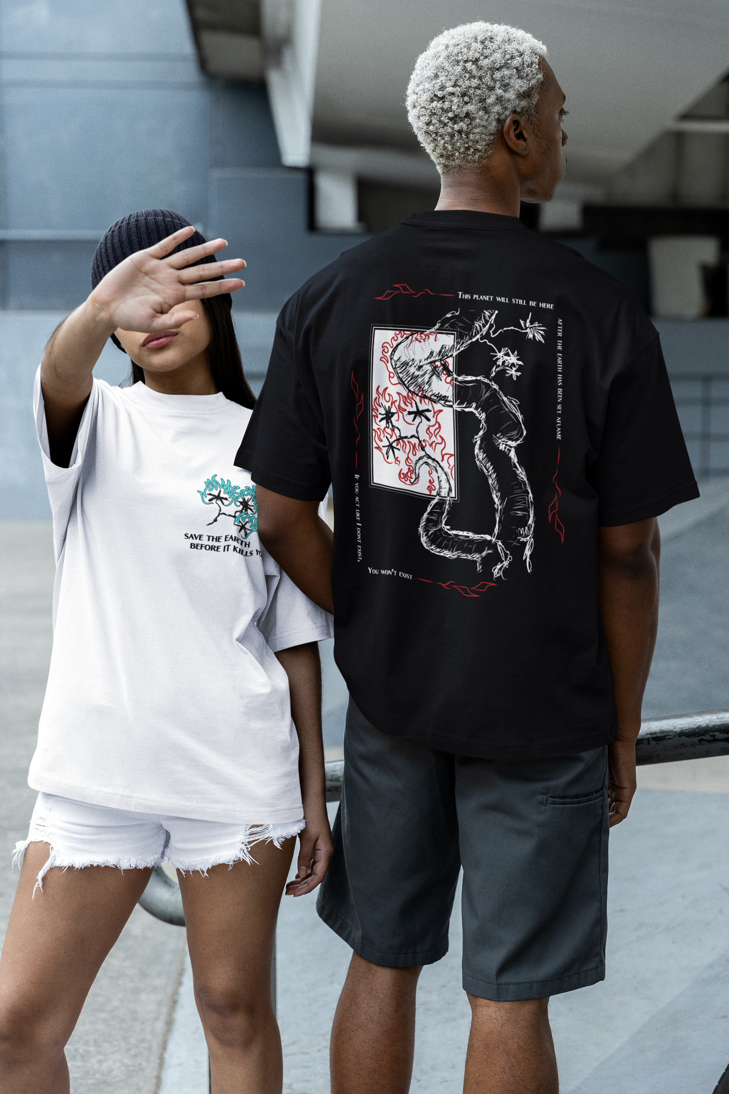Two people wearing graphic t-shirts with designs, one white and one black, standing on a street.