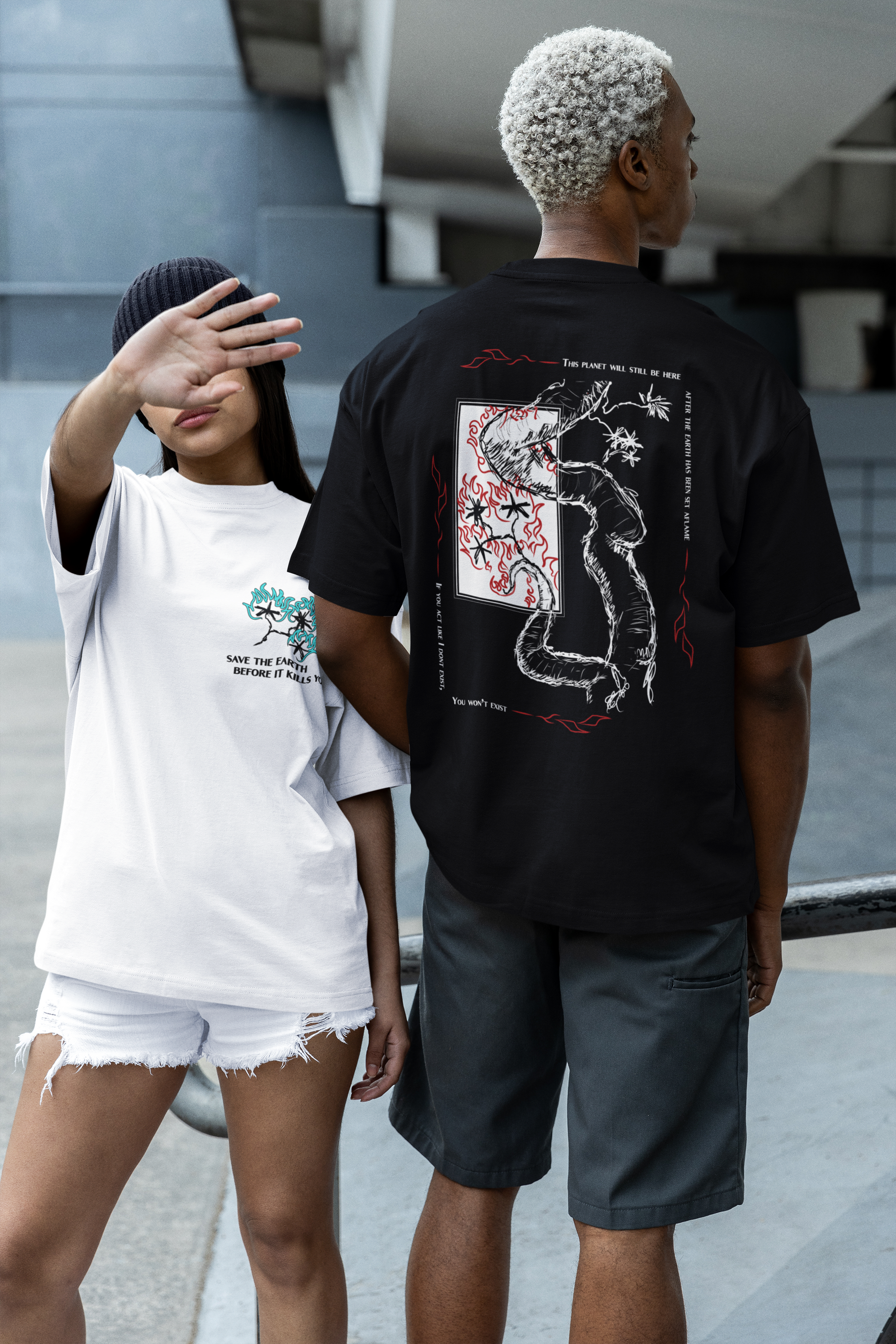 Two people wearing graphic t-shirts with designs, one white and one black, standing on a street.