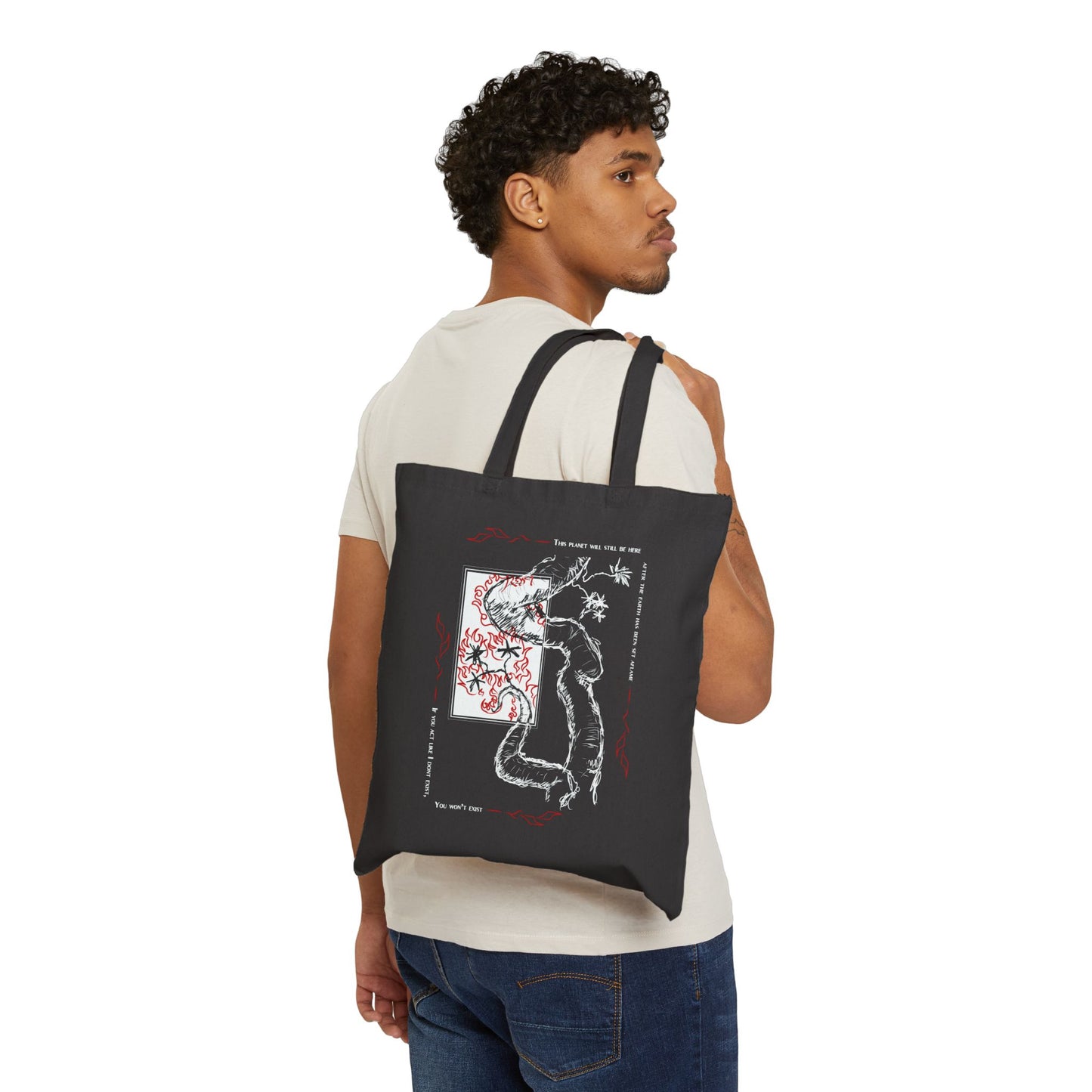 A person carrying a black cotton tote bag with a white and red graphic design on the front.